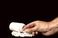 Man's hand holding pill from tablet bottle. Medical concept