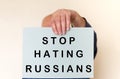 Man hand holding a poster with the inscription Stop Hating Russians