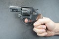 Man`s hand holding a revolver against a gray background, finger on the trigger Royalty Free Stock Photo