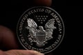 Man's hand holding a silver American coin, close-up of a quarter dollar coin isolated over black. Bag, dollars Royalty Free Stock Photo