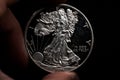 Man's hand holding a silver American coin, close-up of a quarter dollar coin isolated over black. Bag, dollars Royalty Free Stock Photo