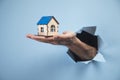 Man`s hand holding a small house on a blue background Royalty Free Stock Photo