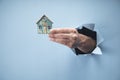 Man`s hand holding a small house on a blue background Royalty Free Stock Photo