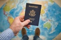Man`s hand holding US passport. Map background. Ready for traveling. Open world Royalty Free Stock Photo