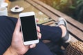 A man`s hand holding white mobile phone with blank black screen in cafe Royalty Free Stock Photo