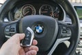 Man`s hand holding a wireless BMW X5 F15 car key in black leather car interior. Modern Car interior details. Car detailing. Car in