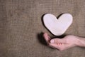 Man`s hand holding wooden heart on natural canvas burlap background. Sustainable eco-friendly Valentine`s day. Earth tone brown Royalty Free Stock Photo