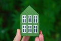 Man`s hand holding wooden house on green background. Sweet home and family concept Royalty Free Stock Photo