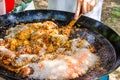 Man`s hand holding wooden turner, mixing uncooked rice with fried chicken meat tomato sauce spices. Preparing paella or jambalaya