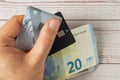 The man`s hand holds bank cards with contactless payment, as well as paper euros. Wooden background. Close-up Royalty Free Stock Photo