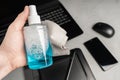 A man`s hand holds a bottle of liquid for cleaning equipment against the background of a laptop, a graphic tablet, a mouse and a