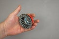 A man`s hand holds a bowl wire brush. A tool for woodworking as well as stripping surfaces of corrosion, scale, or rust. Side vie