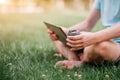 A man`s hand holds a cardboard glass made from recycled material. Man with laptop in the park working concept. Hand with coffee cl