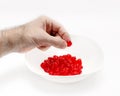 Man's hand holds a cherry over a white bowl with delicious red dried cherries. White background Royalty Free Stock Photo