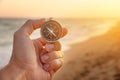 man& x27;s hand holds a compass on the beach. Hand with compass over sand by the sea, direction and adventure concept Royalty Free Stock Photo