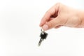 Man`s hand holds the door key to the apartment on a white background