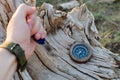 Man`s hand holds a knife for survival stuck in an old, dried tree, next to a compass. Royalty Free Stock Photo