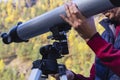 Man\'s hand holds large gray telescope, attaches stargazing equipment to tripod Royalty Free Stock Photo