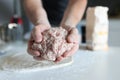 Man`s hand holds minced meat over table where flour is scattered and rolled dough lies Royalty Free Stock Photo