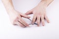 A man`s hand holds a nail clipper, trimming the nails on his thumbs, on a white background Royalty Free Stock Photo
