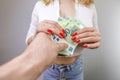 A man's hand holds out hundred euro bills to the girl and she takes them. A girl in jeans with a euro banknote in her hands Royalty Free Stock Photo