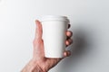 A man`s hand holds a paper coffee Cup on a white background. The concept of Breakfast and coffee. Take the drink with you. Royalty Free Stock Photo