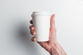 A man`s hand holds a paper coffee Cup on a white background. The concept of Breakfast and coffee. Take the drink with you Royalty Free Stock Photo