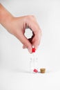 Man`s hand holds a pill over a transparent jar with medicines on a light background close-up. vitamins. pharmaceuticals.