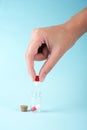 Man`s hand holds a pill over a transparent jar with medicines on a light background close-up. vitamins. pharmaceuticals.