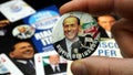 Man`s hand holds a pin from the Forza Italia party founded in 1994 by Silvio Berlusconi