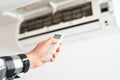 A man& x27;s hand holds a remote control from an air conditioner with a temperature on the screen of 21 Royalty Free Stock Photo