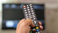 A man`s hand holds the remote from the TV and switches channels. Close-up, moving camera