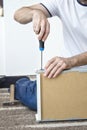 Man`s hand holds the screwdriver and screws the screw that secures the drawer guide. Royalty Free Stock Photo