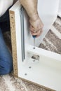 The man`s hand holds the screwdriver and screws the screw that secures the drawer guide. Royalty Free Stock Photo