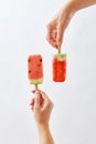 Creative food composition of a fruit ice cream in a female hand and a juicy piece of watermelon on a stick holds a male Royalty Free Stock Photo