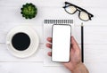 A man's hand holds a smartphone with a blank white screen. Mockup. Workspace of businessman, Royalty Free Stock Photo