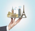A man's hand holds a tablet with sketches of the most famous places in Italy, Great Britain and France. The concept of tourism and