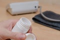 A man`s hand holds a white vial of medicine