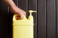 A man`s hand holds a yellow plastic canister with a pump dispenser. A container with a cleaning disinfectant liquid. Sanitary