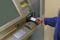 A man\'s hand inserting a blank card into an ATM