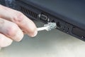 The man`s hand inserts an RJ45 ethernet plug into the internet