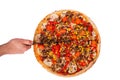 Man`s hand with a knife cut the pizza with mushrooms, corn, cherry tomatos, courgettes and bell peppers or Veggie Vegetarian pizza