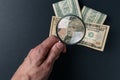 Man`s hand with magnifying glass and money on black background. Paper currency. Looking For Money. Concept of search Royalty Free Stock Photo