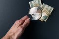 Man`s hand with magnifying glass and money on black background. Paper currency. Looking For Money. Concept of search Royalty Free Stock Photo