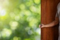 Hand opening old wooden door on blurred fresh green bokeh background