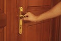 Man`s hand opening wooden door. Holding a gold door handle. Royalty Free Stock Photo