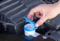 The man& x27;s hand opens the filler neck for filling the windshield washer fluid of a passenger car. Close-up Royalty Free Stock Photo