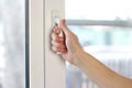 A man`s hand opens a white plastic window. Close up