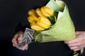 A man`s hand pays for a bouquet of yellow tulips for the holiday of March 8. Royalty Free Stock Photo