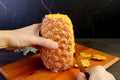 Man`s hand peeling a fresh ripe pineapple with knife on the cutting board Royalty Free Stock Photo